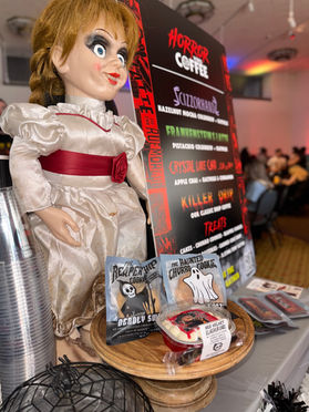 Horror Vibes Coffee display featuring an Annabelle doll and themed menu